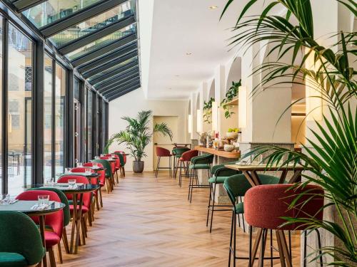 Un restaurante con mesas, sillas y plantas. en Hotel Giacomo Morra Alba - Handwritten Collection, en Alba