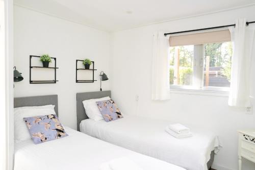 twee bedden in een witte kamer met een raam bij Chalet met hottub in Putten