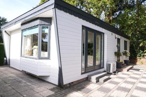a white tiny house with a black roof at Boshuisje de Kastanje - Chalet met prive hottub in Putten