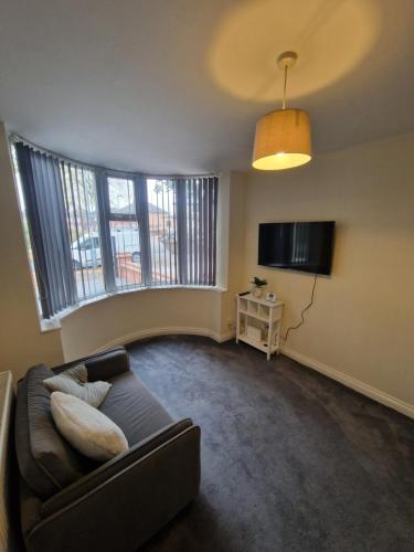 a living room with a couch and a flat screen tv at Sheldon Apartments BHX HS2 JLR NEC in Birmingham