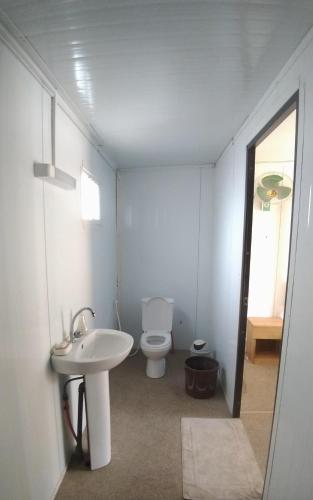 a bathroom with a white toilet and a sink at Gîte Daline Guenaar in Niodior