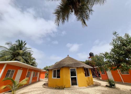 NiodiorGîte Daline Guenaar的一座黄色的小建筑,屋顶茅草