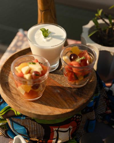 a tray with three bowls of fruit and a bowl of yogurt at Zambezi Dusk River Facing-all inclusive-Luxury Accommodation in Livingstone