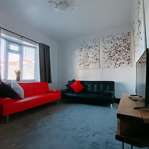a living room with a black couch and a red couch at Geneva Cottage - close to Darlington train station in Darlington