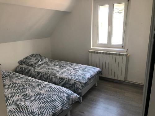 two beds in a small room with a window at Maison individuelle avec Jardinet in Arques-la-Bataille