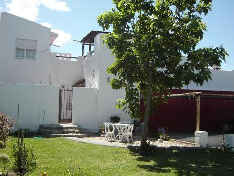 a white house with a table and a tree in the yard at La Vecindad del Sol depto I in Miramar