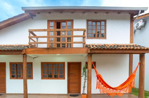 a white house with an orange hammock in front of it at BC Praia Estaleiro - 2 Vagas, Ar, Churras e Pet OK in Balneário Camboriú