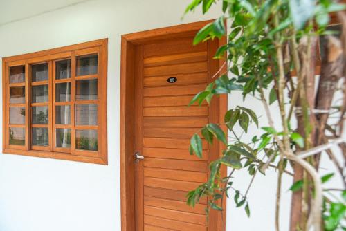 a wooden door with a window and a plant at BC Praia Estaleiro - 2 Vagas, Ar, Churras e Pet OK in Balneário Camboriú