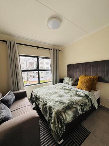 a bedroom with a large bed and a window at Right at home in Boksburg