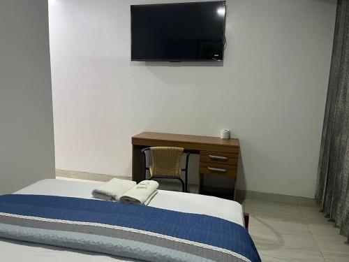 a bedroom with a bed and a desk and a television at Hostal Huella in Lambayeque