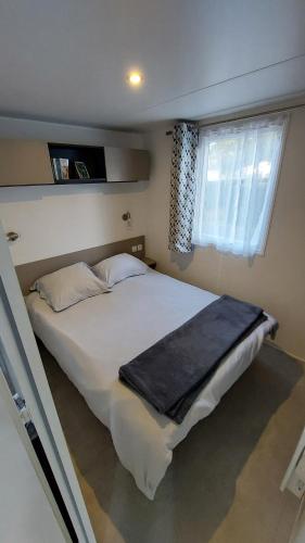 a large white bed in a bedroom with a window at Mobilhome 3 chambres TV-WIFI-Lave-linge in Pont-Aven