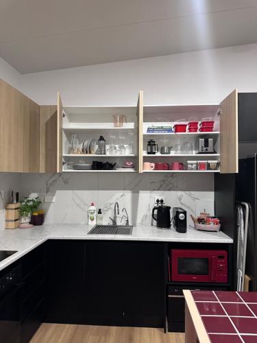 a kitchen with black cabinets and a red microwave at Aurora Self Contained Studio in Brisbane