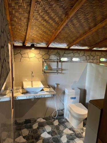 a bathroom with a white toilet and a sink at Ananda Bungalow Tetebatu in Tetebatu