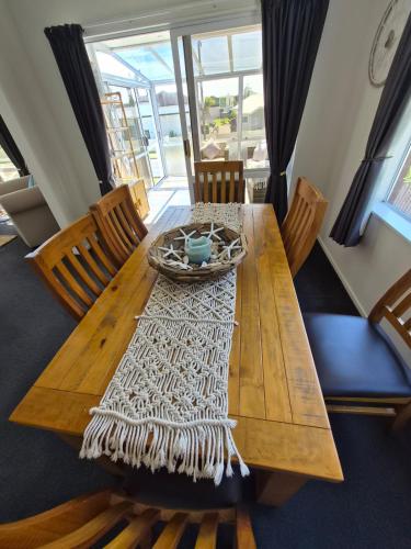 una mesa de madera con sillas y un bol en la parte superior en Ohope Ocean Breeze Escape, en Ohope Beach