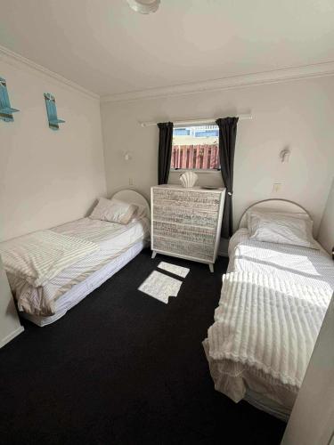 Un dormitorio con dos camas y una ventana. en Ohope Ocean Breeze Escape, en Ohope Beach