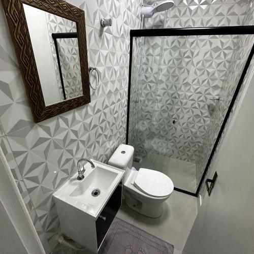 a bathroom with a toilet and a sink and a mirror at Loft Lux SM 07 (Smart TV, Ar condicionado, Cozinha) in Chapecó
