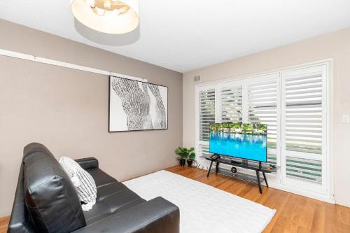 a living room with a black leather couch and a tv at Wagga Central Apartments in Wagga Wagga