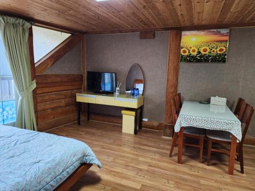 Un dormitorio con una cama, una mesa y un televisor. en 단양추억펜션, en Paegam