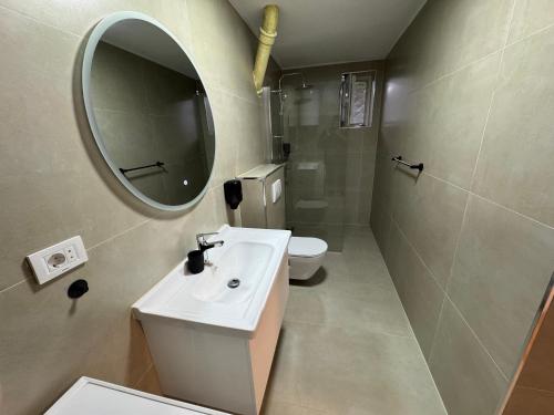 a bathroom with a sink and a mirror and a toilet at Meet Prishtina Apartments in Pristina