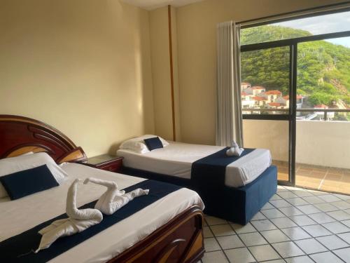 a hotel room with two beds and a large window at Apartamento Rodadero para vacacionar in Gaira