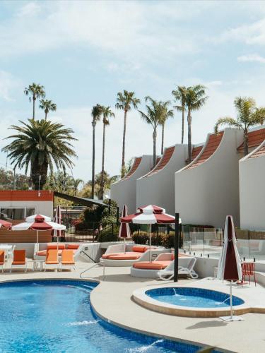 a resort pool with chairs and umbrellas and palm trees at Lake Mulwala Boatel in Mulwala