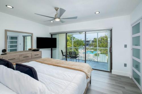 a bedroom with a bed and a tv and a balcony at Tropical 2BR2BA Getaway in Gorgeous Key Largo, Marina, Saltwater Lagoon, Pool in Key Largo