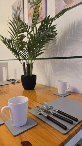 a table with two cups and a potted plant on it at Spacious Entire House with Free Parking Perfect for Relocators Contractors and Long Term Stays in Bury