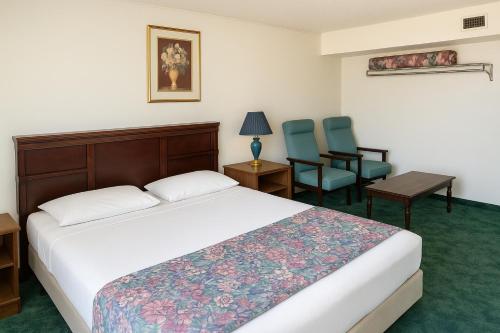 a hotel room with a bed and two chairs at Economy Inn in Temple