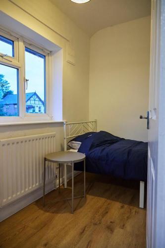 a bedroom with a bed and a table and a window at Stylish Wembley Home with Hot Tub, Parking & Garden in London