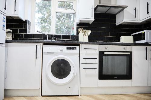 eine weiße Küche mit Waschmaschine in der Unterkunft Stylish Wembley Home with Hot Tub, Parking & Garden in London