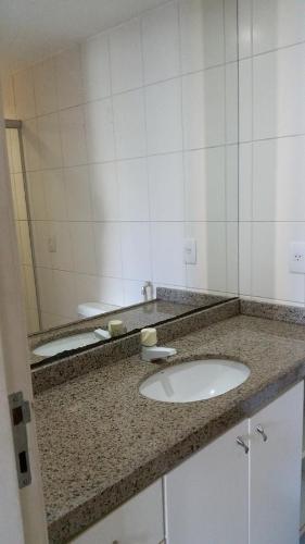 eine Badezimmertheke mit einem Waschbecken und einem Spiegel in der Unterkunft Amazonia Residence 3 Quartos in Fortaleza
