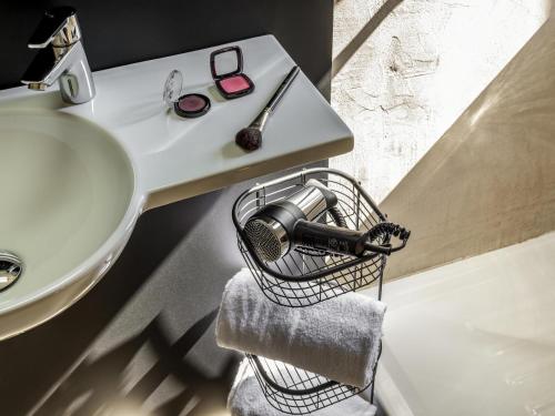 a bathroom with a sink and a basket with a hair dryer at ibis Styles Boulogne sur Mer Centre Cathédrale in Boulogne-sur-Mer
