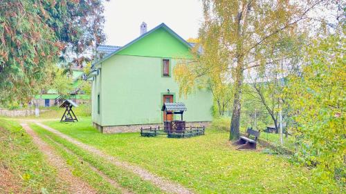 a green house in the middle of a yard at Goryanka family home in Mykulychyn