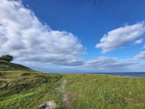 een groene heuvel met een blauwe lucht en wolken bij 4 person holiday home in Grenaa in Grenå