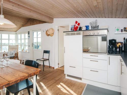 a kitchen with white cabinets and a wooden table at 4 person holiday home in Grenaa in Grenå