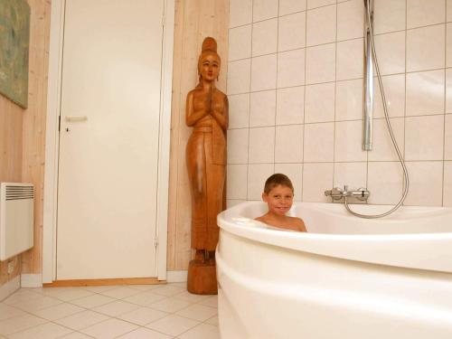 Un niño sentado en una bañera junto a una estatua en 6 person holiday home in Dronningmølle-By Traum, en Gilleleje