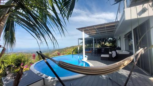 a hammock on the deck of a house with a pool at Palco Pacifico at The Retreat in Atenas