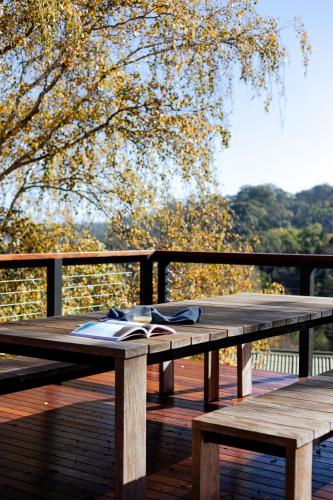a wooden picnic table with a book on it on a deck at Whistlewood - Stunning Views in the Adelaide Hills in Upper Sturt