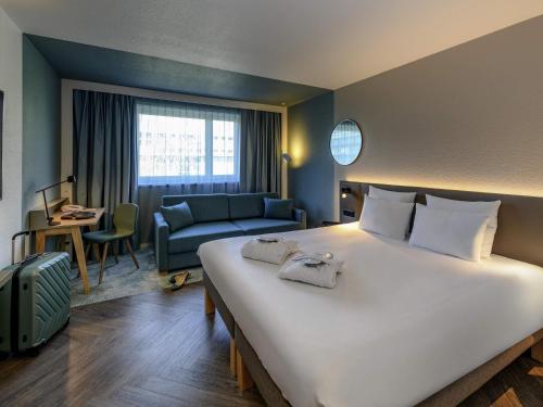a hotel room with a large bed and a couch at Novotel Zurich City West in Zurich