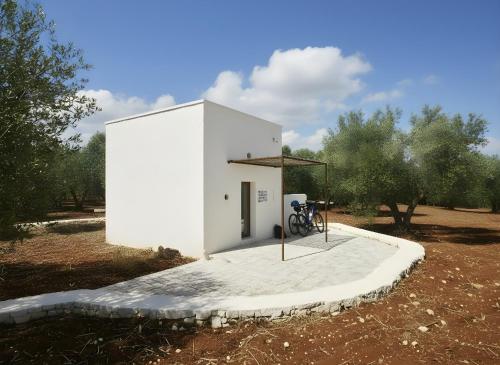 een klein wit gebouw met een fiets ervoor bij La Posta dell'Eremo in Ostuni