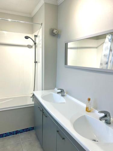 a bathroom with two sinks and a mirror and a shower at Relaxing rooms with mountain views, close to ferry in Wellington