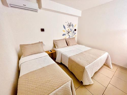 two beds in a room with white walls at Pousada Solana in Salvador