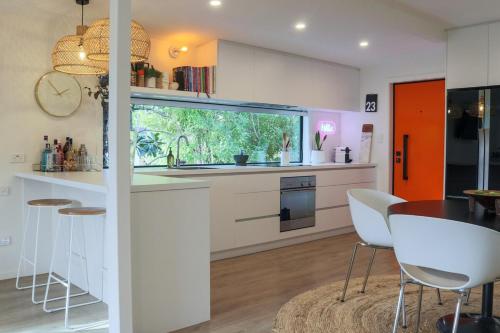 ブレナムにあるHome in Sunny Marlborough!の白いキャビネットとテーブルと椅子のあるキッチン