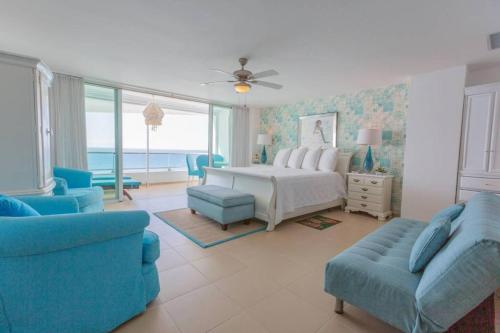 een slaapkamer met een bed en een bank en stoelen bij Luxury Penthhouse Frente Al Mar in Villas del Mar