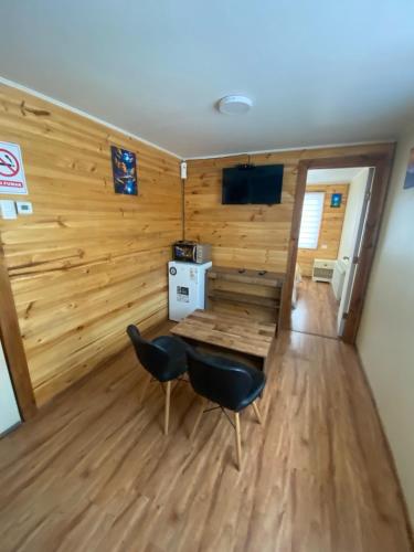 a room with a table and chairs in a room with wooden walls at Departamento Marve in Puerto Natales