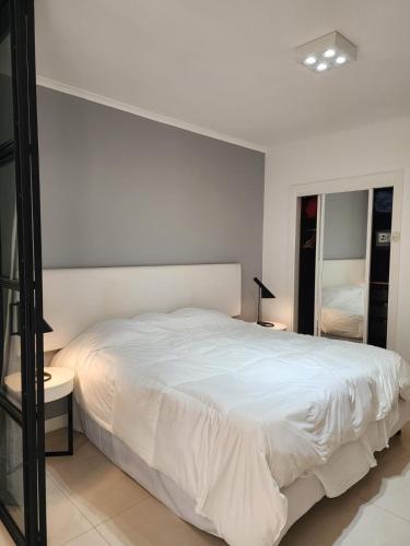a bedroom with a white bed and a mirror at Green Park hermoso apartamento vista al lago in Punta del Este