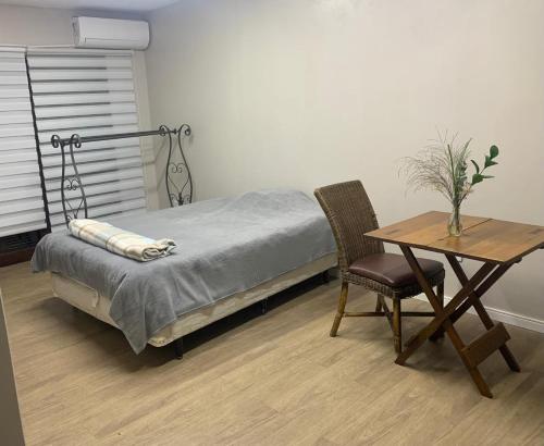 een slaapkamer met een bed en een tafel met een stoel bij House Bela Vista in Porto Alegre