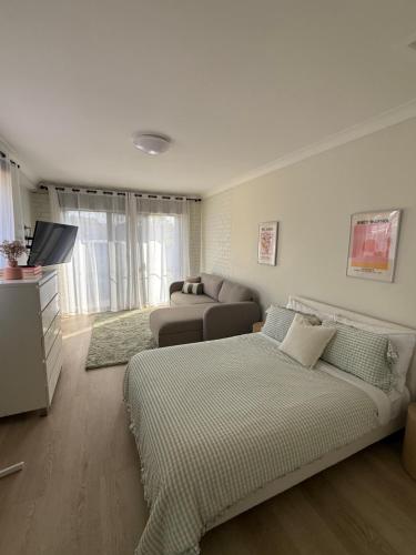 a living room with a bed and a couch at Forster Holiday Home Cozy, Central & Near Beach in Forster