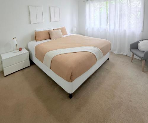 a white bedroom with a large bed and a chair at Cozy Stay in Forster in Forster