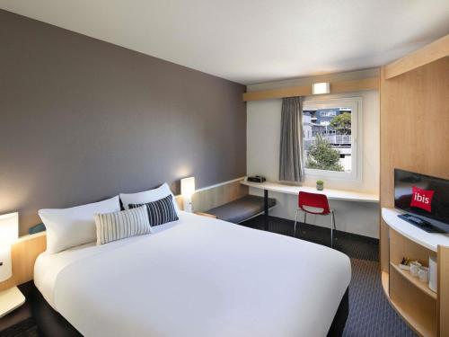 a hotel room with a white bed and a window at ibis Thornleigh in Thornleigh